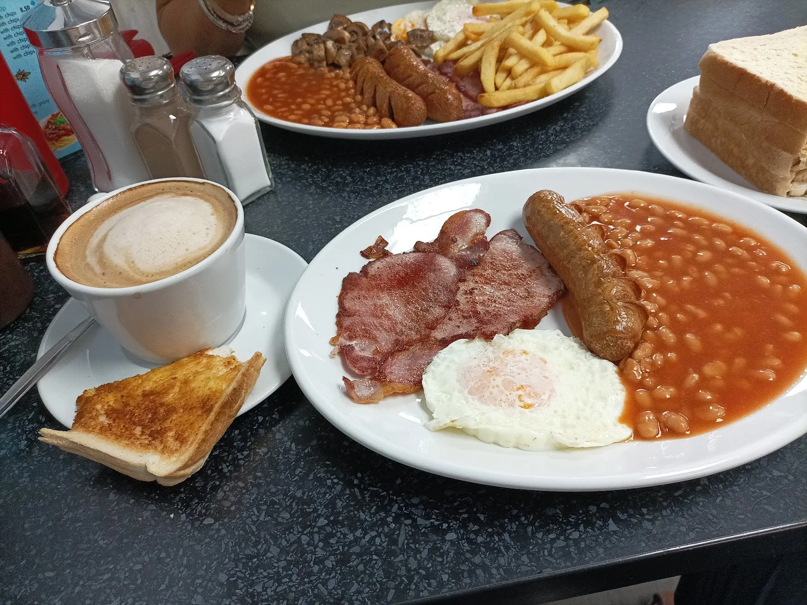 A set breakfast at Station Cafe: bacon, sausage, fried egg and beans with toast and a mug of coffee