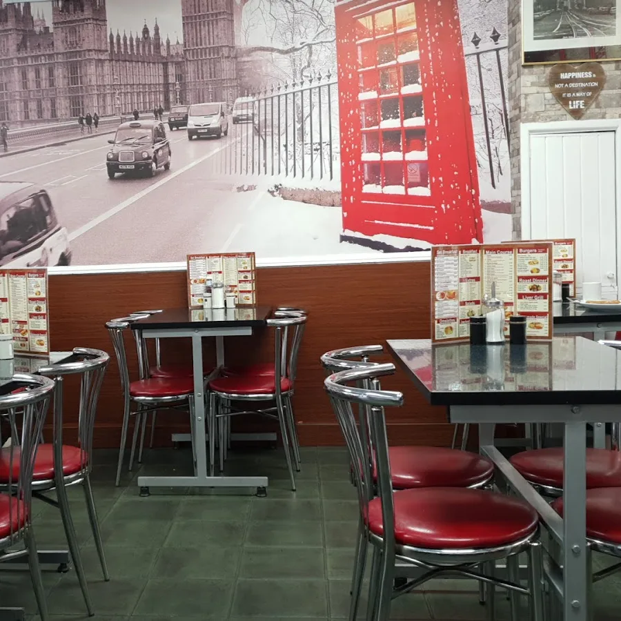 Inside Station Cafe: red chairs, dark tables and the London mural with the red bus and phone box